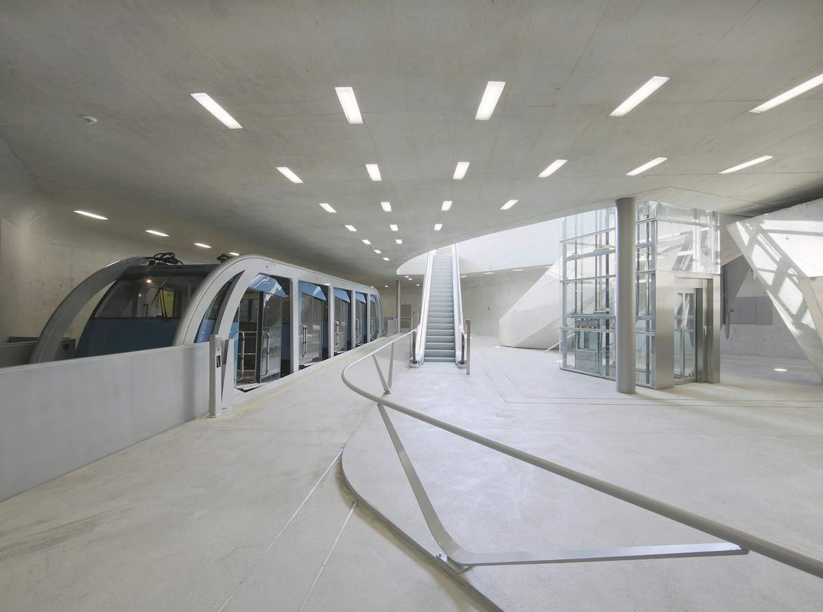 Innsbruck to Hungerburgbahn: Roundtrip Funicular Ride Modern indoor train station with a sleek monorail, escalators, and glass-enclosed elevator. Bright lighting from ceiling fixtures.