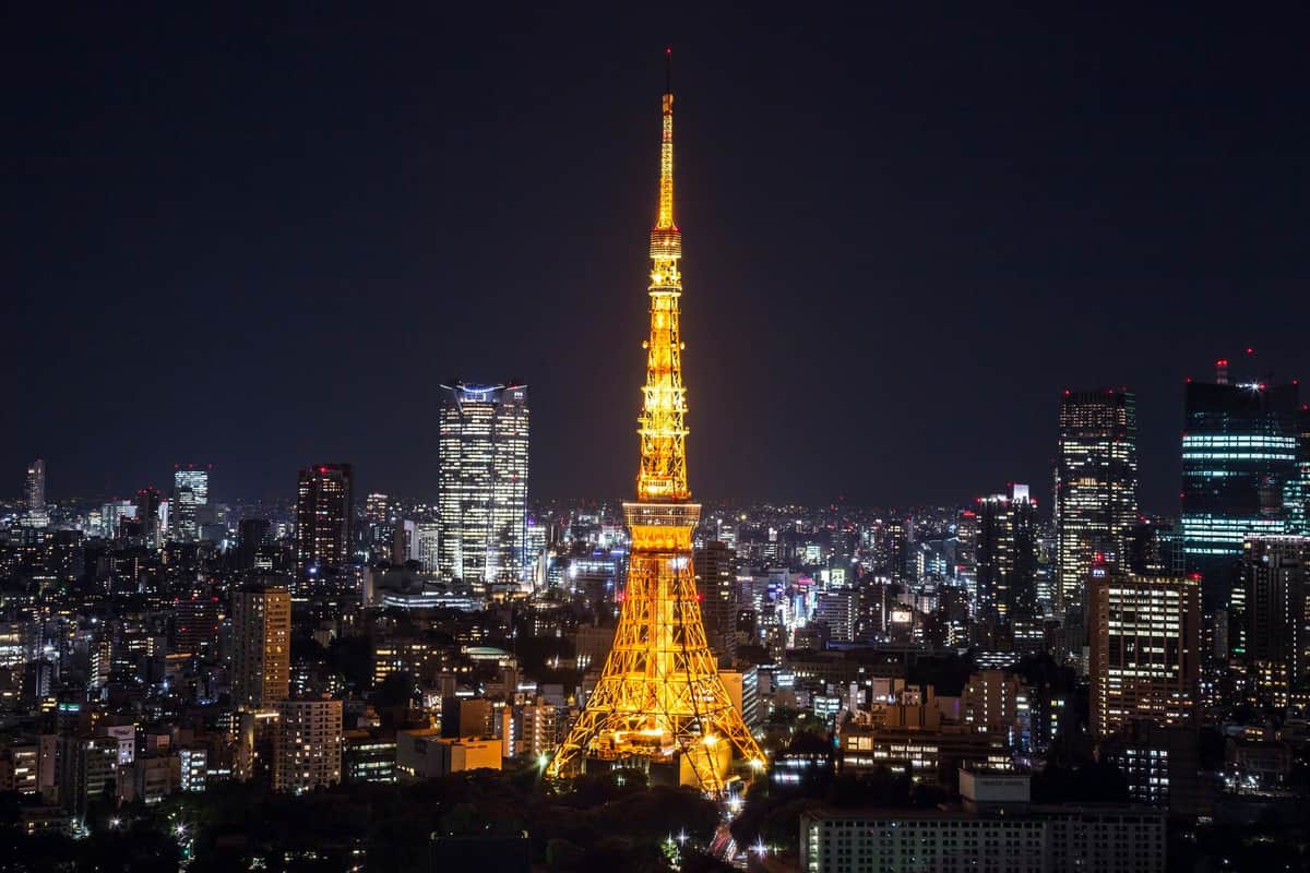 Tokyo Tower: Main Deck Admission + Tokyo Subway Ticket Tall illuminated tower at night in a city skyline with numerous buildings and lights.