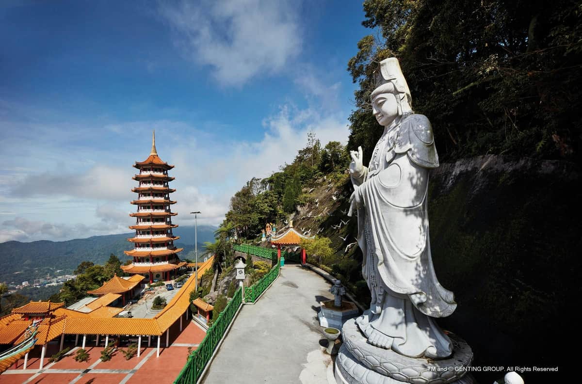 Genting Highlands: bilet w jedną stronę na standardową gondolę Awana SkyWay Duży biały posąg bóstwa w pobliżu tradycyjnej pagody i ścieżki, ustawiony na zboczu wzgórza z zielenią i czystym niebem.