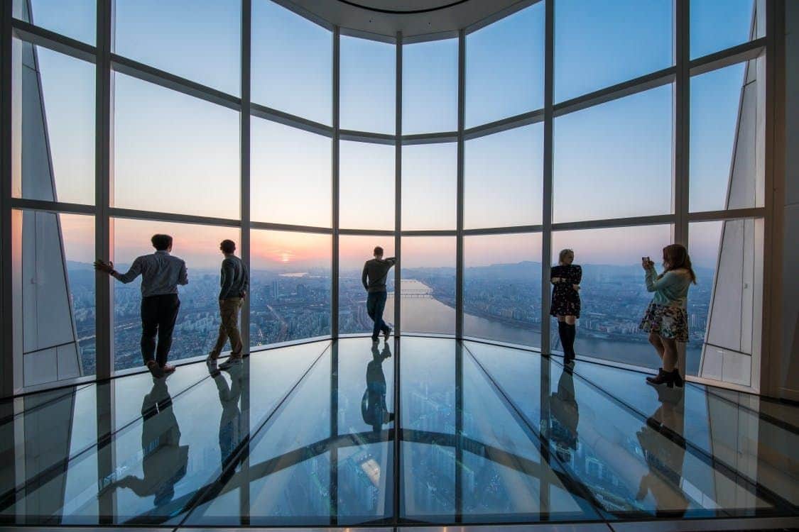 A tall skyscraper with surrounding city lights and traffic, under a twilight sky.