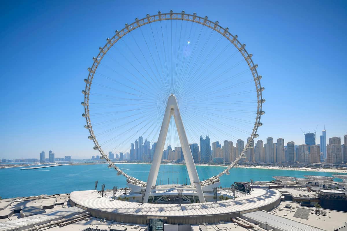 アイン・ドバイ: 大観覧車チケット 澄んだ青空の下、街のスカイラインが背景にあるウォーターフロント沿いの大きな観覧車。