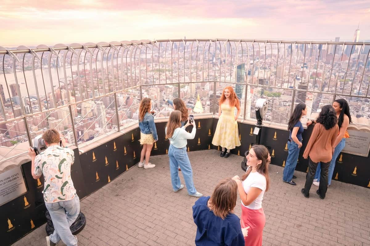 People enjoying the view from an observation deck at sunset, with a cityscape visible through the railing.