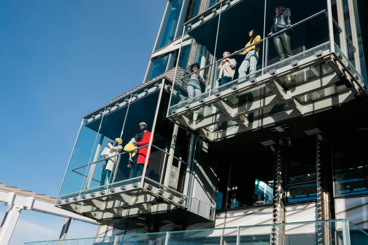 SUMMIT One Vanderbilt: Entry Ticket + Ascent People standing on modern glass balconies attached to a building, with a clear blue sky in the background.