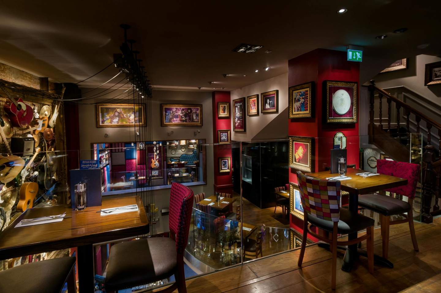 Hard Rock Cafe Brussels Restaurant interior with framed pictures on the walls, tables set for two, and eclectic seating in a dimly lit, cozy atmosphere.