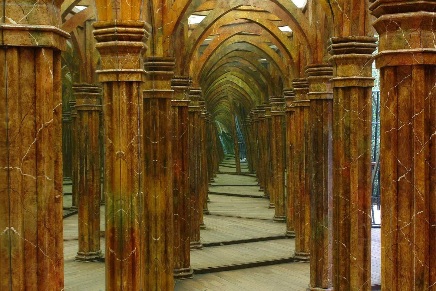 A mirrored hallway with numerous brown, marble-like columns reflecting infinitely, creating an intricate pattern.