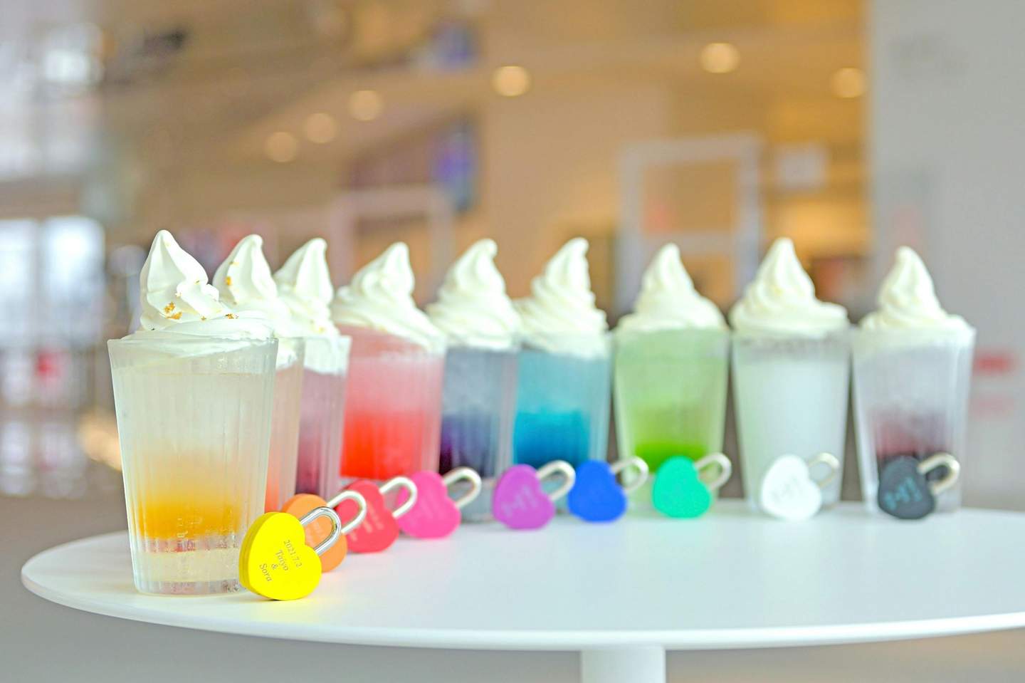 梅田スカイビル&空中庭園展望台 白いテーブルにソフトクリームをトッピングしたカラフルな飲み物が並び、それぞれにハート型のロックが付いています。