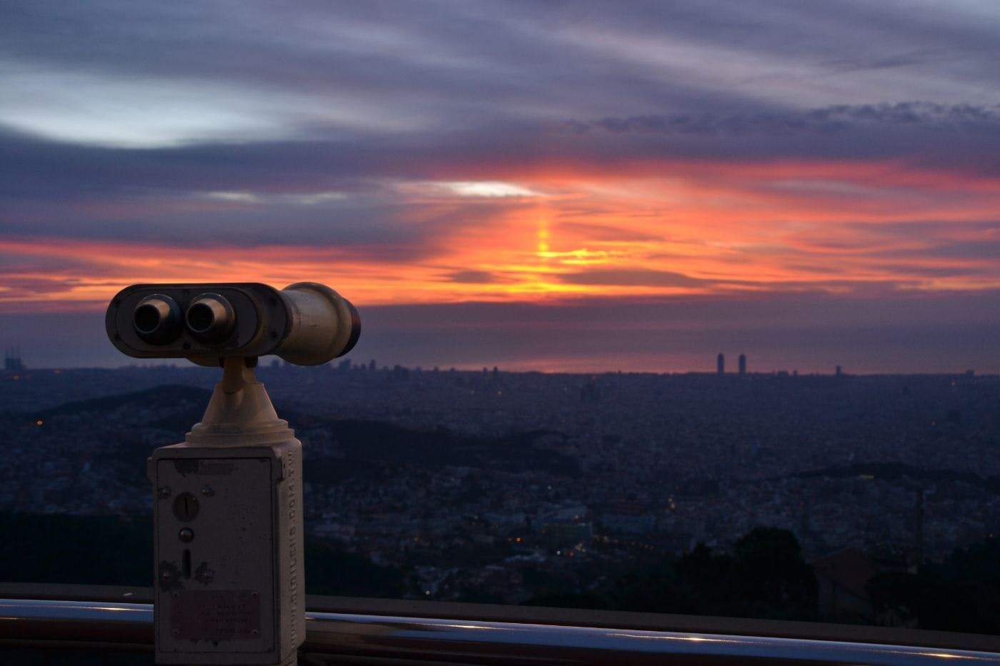 Tibidabo Panorama Area A scenic view of the city at sunset with a binocular viewer in the foreground.