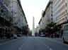Obelisco de Buenos Aires Observatiedek Ticket (Buenos Aires) Brede straat geflankeerd door hoge gebouwen, centrale obelisk in de verte, licht verkeer met bussen, auto's en voetgangers, bomen langs de weg.